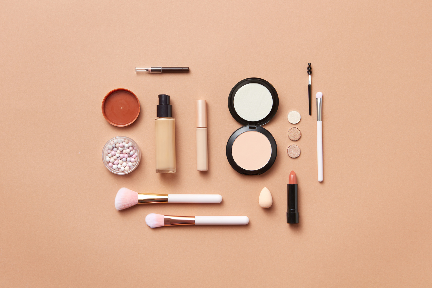 Makeup and Makeup Brushes on Orange Background